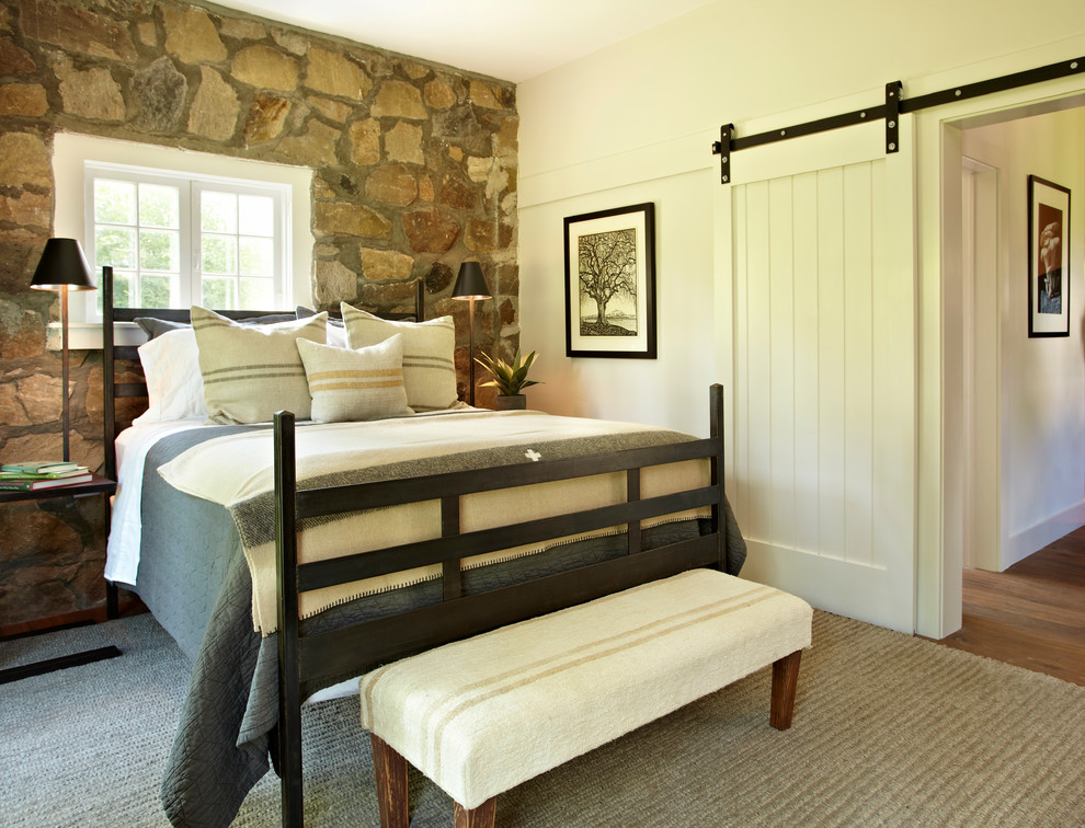 Ejemplo de dormitorio rural sin chimenea con paredes blancas y suelo de madera en tonos medios