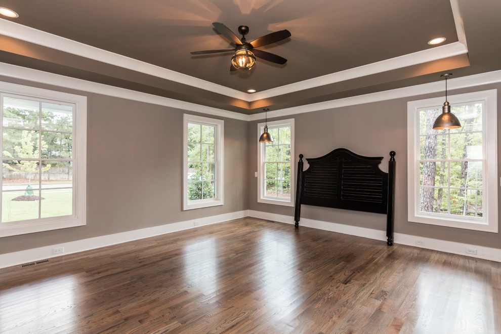 Large cottage master medium tone wood floor bedroom photo in Raleigh with gray walls
