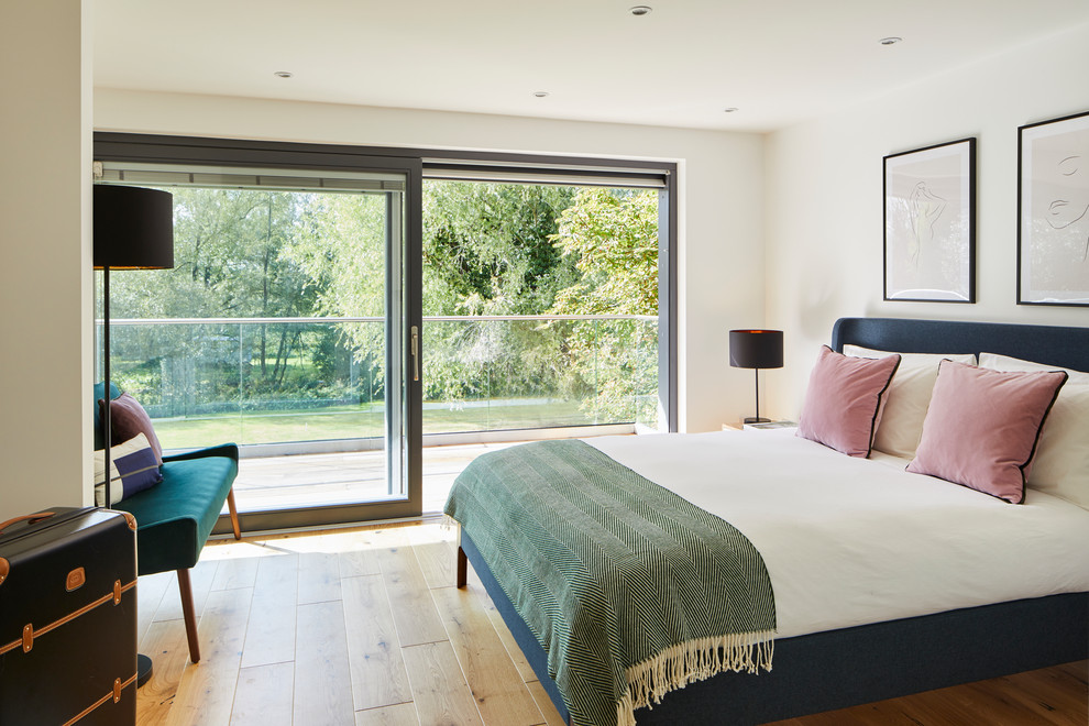 Inspiration for a contemporary bedroom in London with white walls, light hardwood flooring and no fireplace.