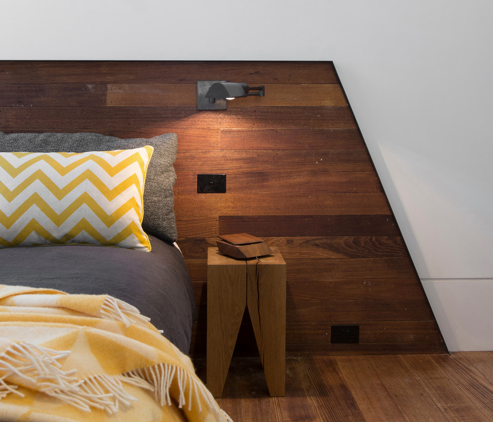 Cette image montre une chambre parentale design avec un mur blanc et un sol en bois brun.