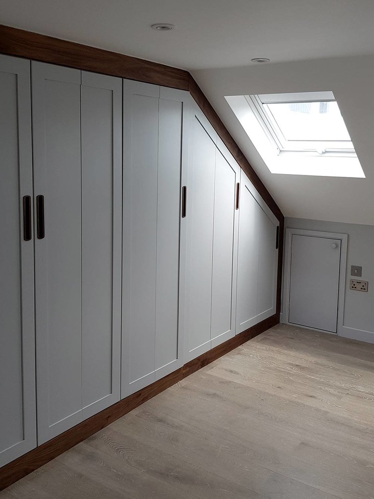 Diseño de habitación de invitados contemporánea pequeña con paredes blancas, suelo de madera clara y suelo beige