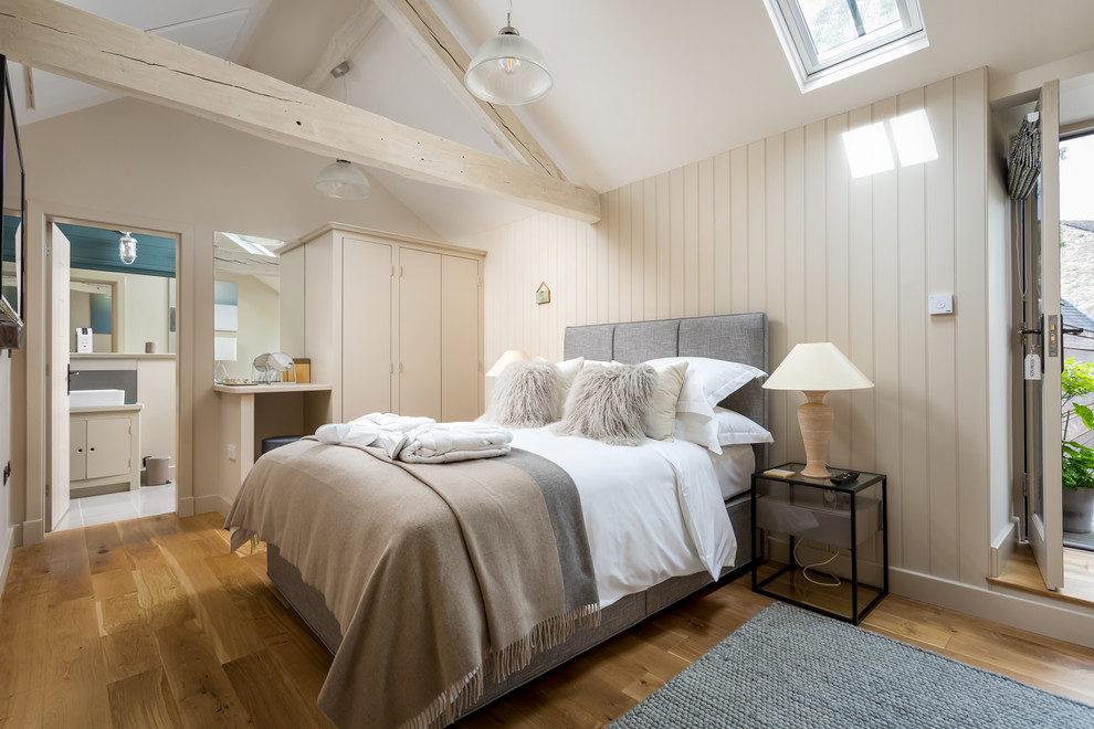 Ejemplo de dormitorio principal campestre de tamaño medio con paredes beige y suelo marrón