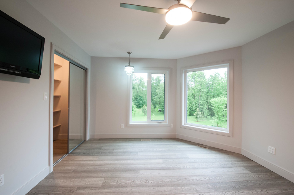 Foto de dormitorio principal actual de tamaño medio con paredes grises, suelo laminado y suelo gris
