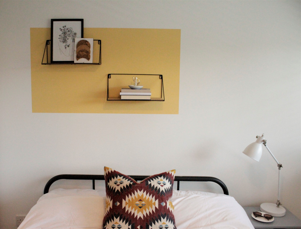 カーディフにある広いミッドセンチュリースタイルのおしゃれな主寝室 (黄色い壁、ラミネートの床、暖炉なし、茶色い床)
