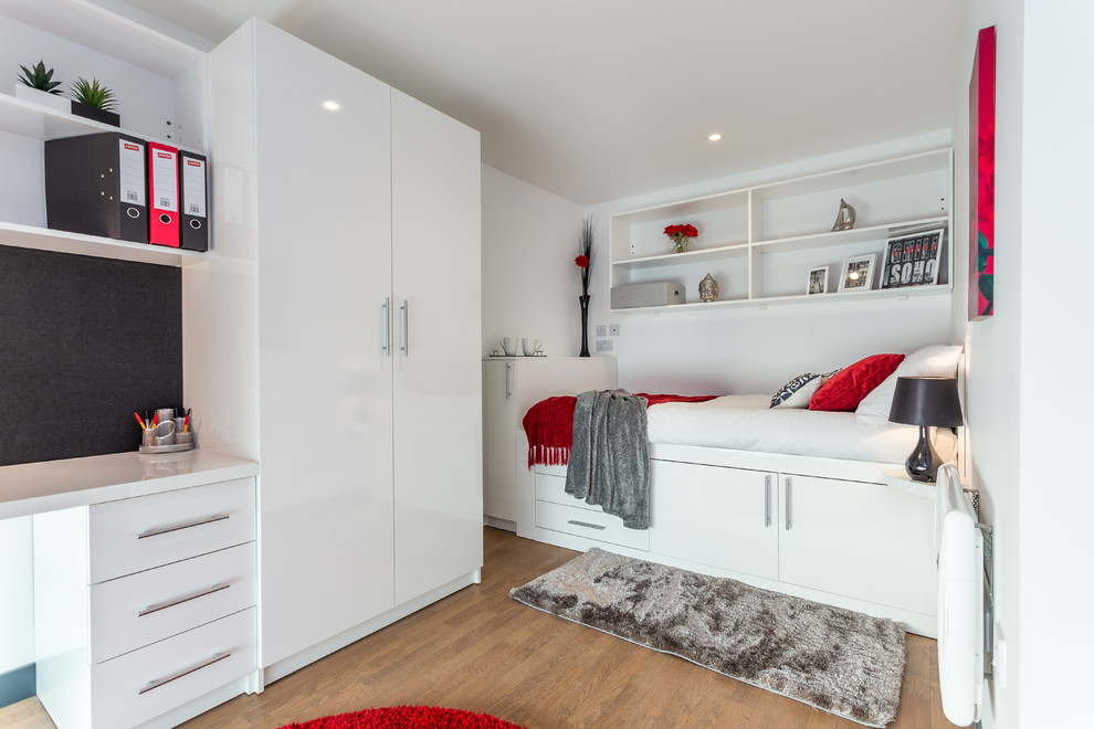 This is an example of a contemporary bedroom in Dorset with white walls and medium hardwood flooring.