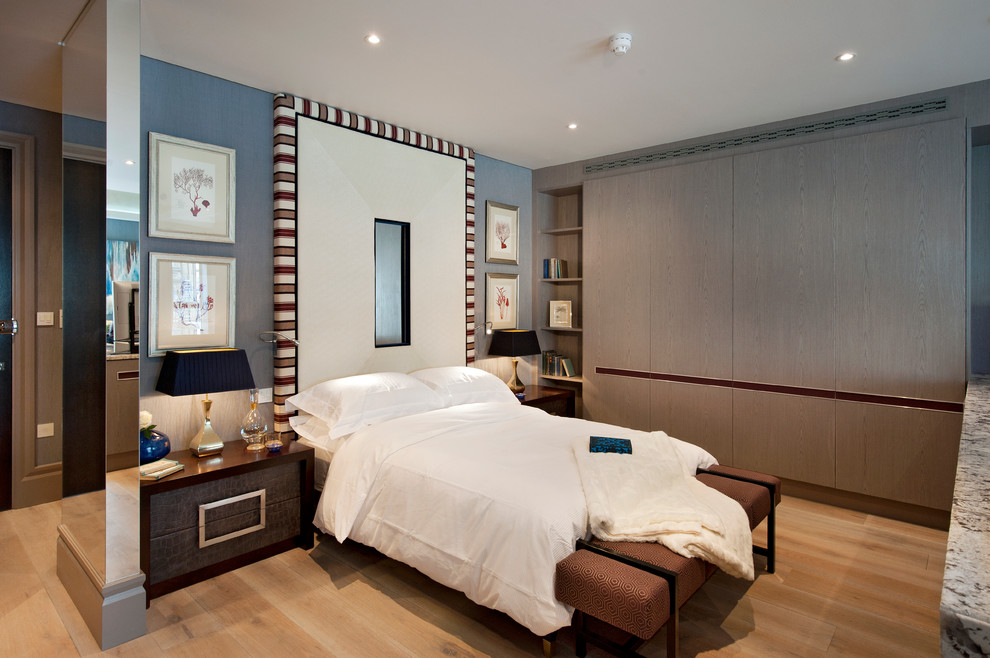 Design ideas for a contemporary bedroom in London with blue walls, medium hardwood flooring and brown floors.