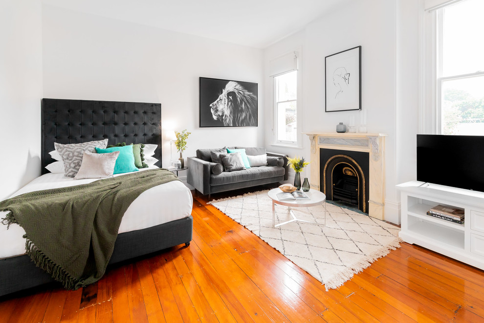 Nordisches Schlafzimmer mit weißer Wandfarbe, braunem Holzboden, Kamin und braunem Boden in Sydney