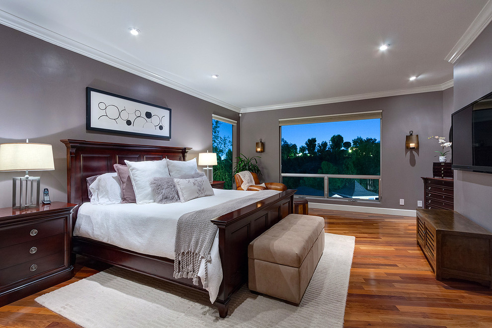 Diseño de dormitorio principal y televisión clásico con paredes grises y suelo de madera en tonos medios
