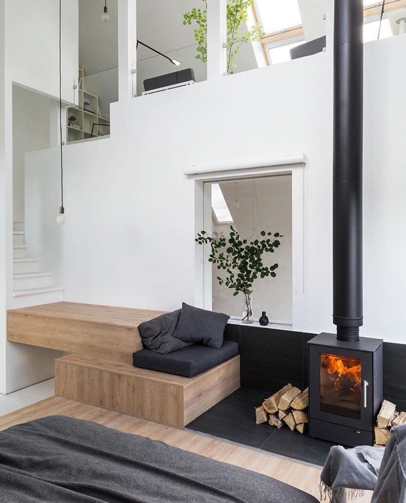 Idee per una piccola camera da letto scandinava con pareti bianche, parquet chiaro e stufa a legna