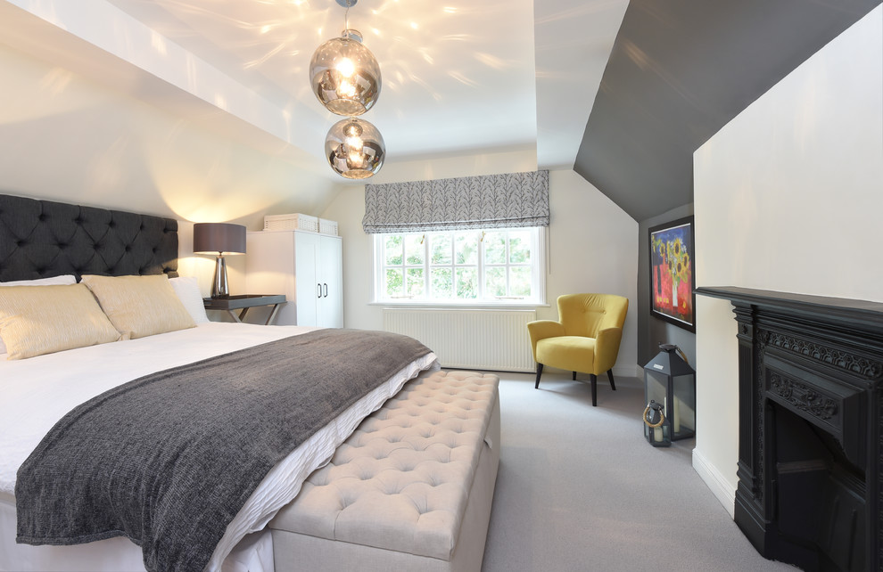 マンチェスターにあるトランジショナルスタイルのおしゃれな寝室 (白い壁、カーペット敷き、標準型暖炉、木材の暖炉まわり、グレーの床)