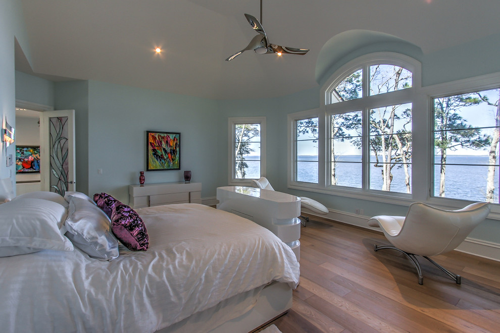 Imagen de dormitorio principal tradicional renovado de tamaño medio con paredes azules, suelo de madera en tonos medios, todas las chimeneas y marco de chimenea de madera