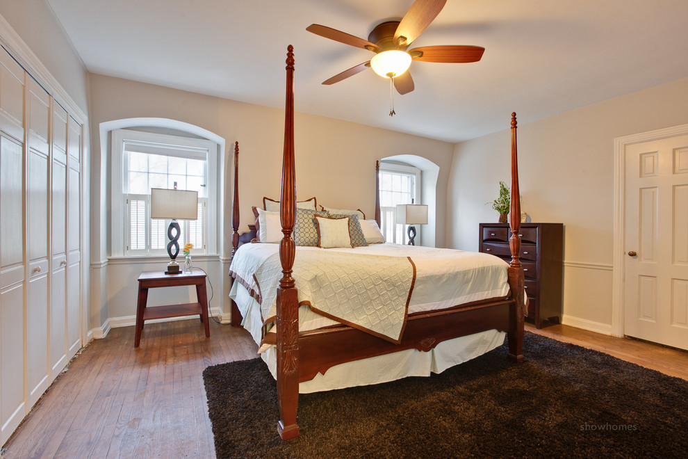 Modelo de dormitorio principal clásico renovado con paredes grises y suelo de madera en tonos medios