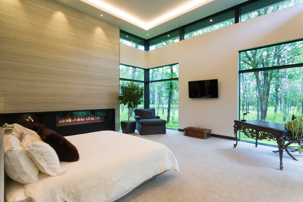 Стильный дизайн: огромная хозяйская спальня в современном стиле с ковровым покрытием, стандартным камином, фасадом камина из плитки, желтыми стенами и бежевым полом - последний тренд