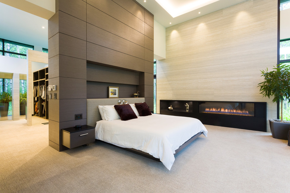 This is an example of an expansive contemporary master bedroom in Other with white walls, carpet, a ribbon fireplace, a tiled fireplace surround and beige floors.