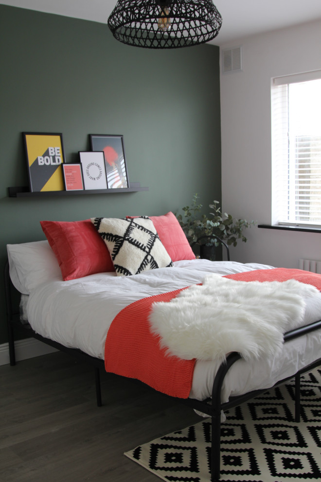 Imagen de habitación de invitados minimalista de tamaño medio sin chimenea con paredes verdes, suelo laminado y suelo marrón