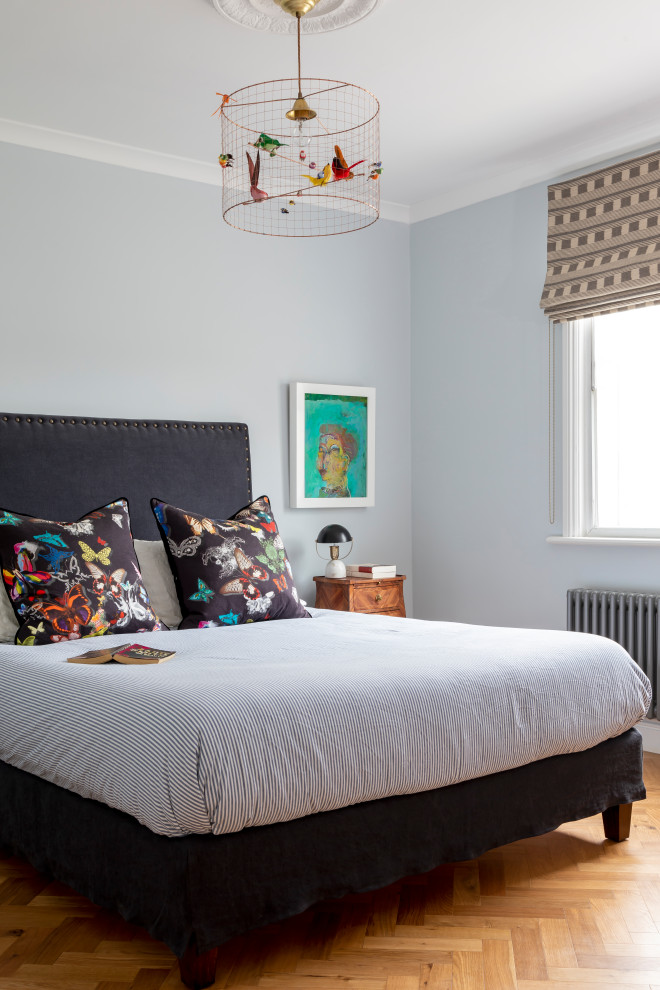 Bohemian grey and brown bedroom in London with grey walls, medium hardwood flooring and brown floors.