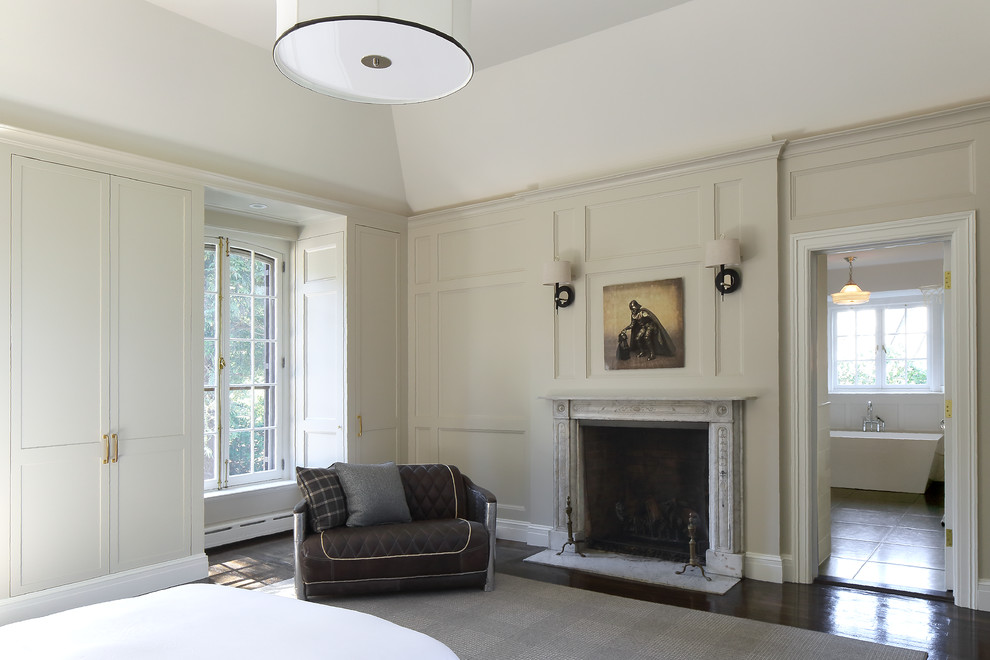 Idée de décoration pour une grande chambre d'amis tradition avec un mur beige, parquet foncé, une cheminée standard et un manteau de cheminée en plâtre.