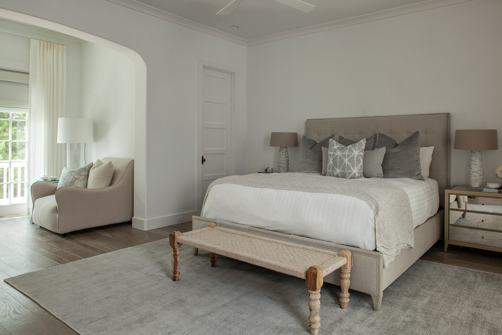 Modelo de dormitorio principal clásico renovado grande sin chimenea con paredes blancas, suelo de madera en tonos medios y suelo marrón
