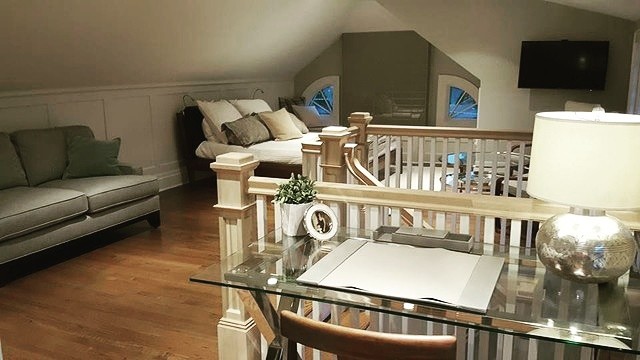 Immagine di una piccola camera da letto stile loft country con pareti bianche, parquet chiaro, soffitto a volta e pannellatura