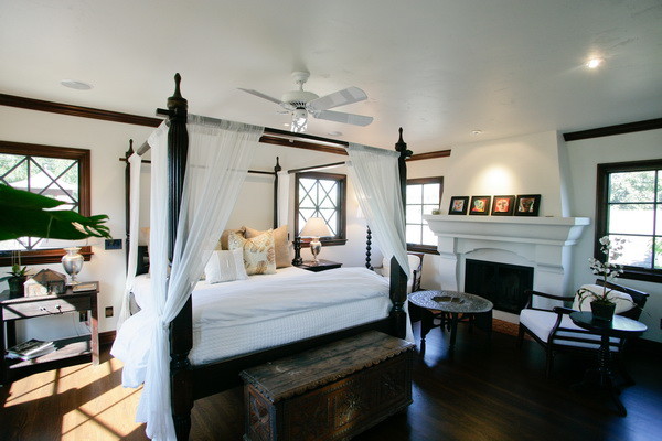 Imagen de dormitorio principal grande con paredes blancas, suelo de madera oscura, todas las chimeneas y marco de chimenea de yeso