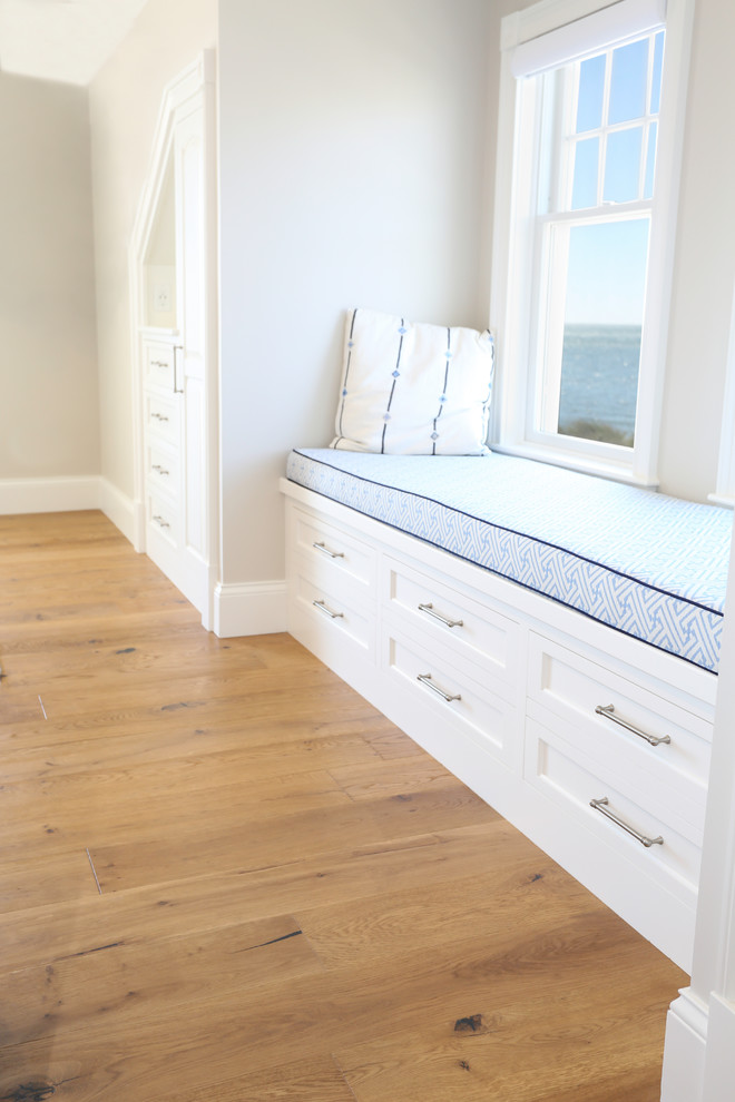 Ejemplo de dormitorio principal costero grande sin chimenea con paredes grises, suelo de madera en tonos medios y suelo marrón