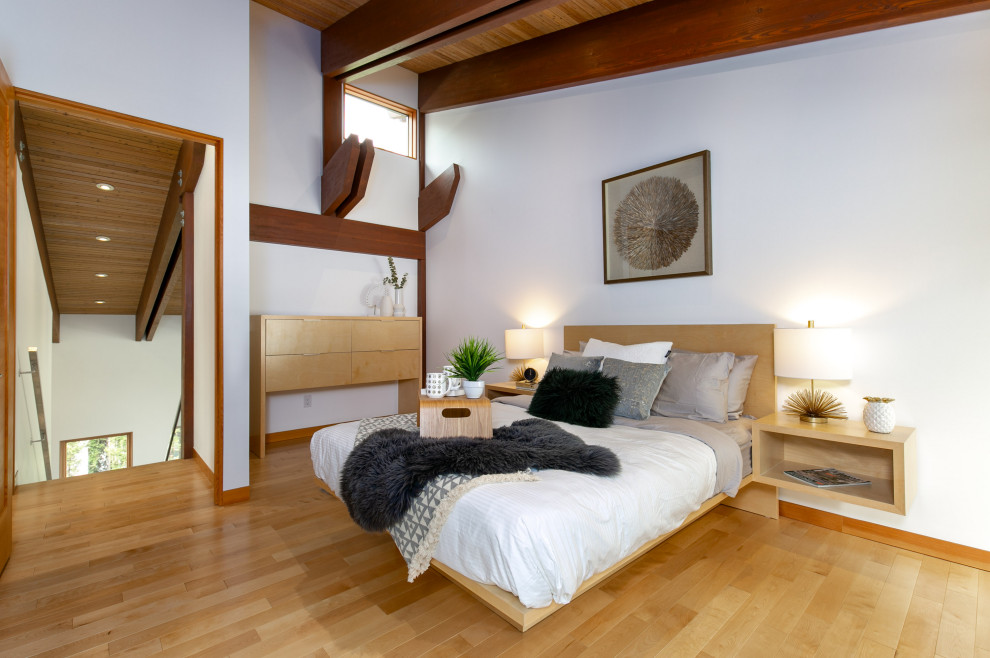 Imagen de dormitorio principal retro sin chimenea con paredes blancas, suelo de madera clara y vigas vistas