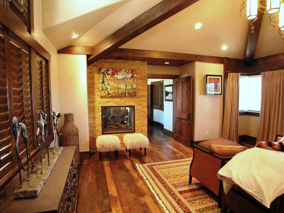 Modelo de dormitorio principal rural grande con suelo de madera en tonos medios