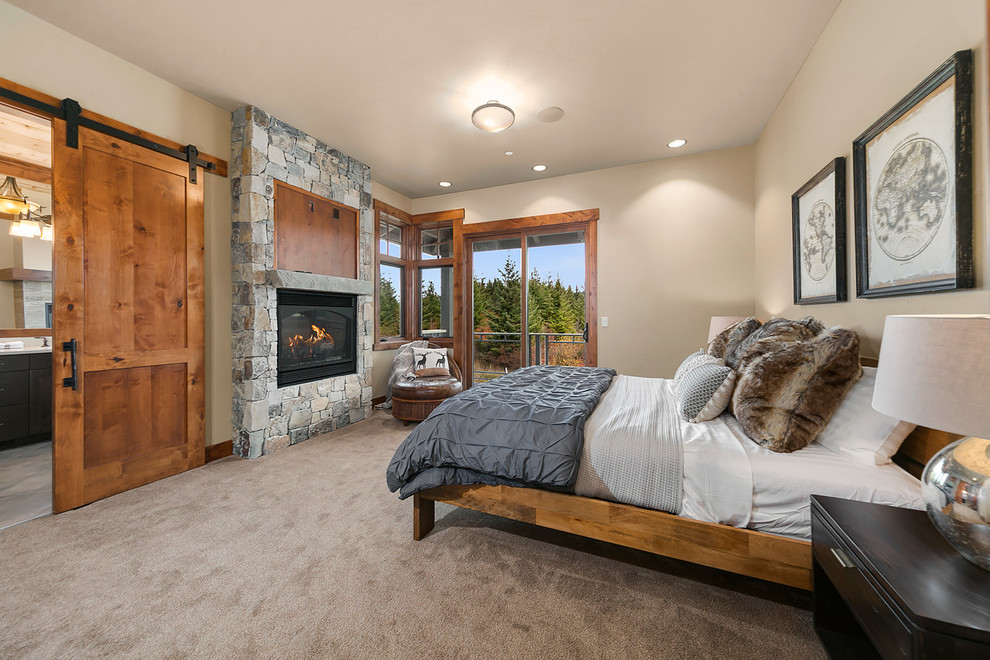 シアトルにあるラスティックスタイルのおしゃれな主寝室 (カーペット敷き、白い壁、横長型暖炉、石材の暖炉まわり、ベージュの床、グレーとブラウン) のインテリア