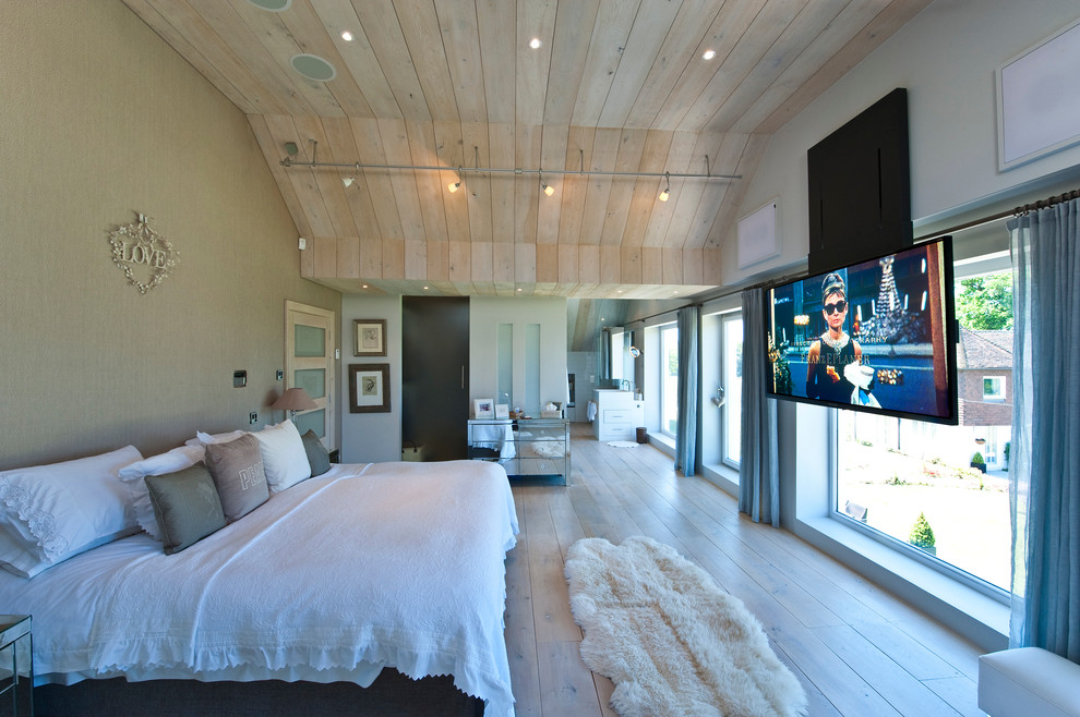 На фото: большая хозяйская спальня в современном стиле с бежевыми стенами, светлым паркетным полом и телевизором с