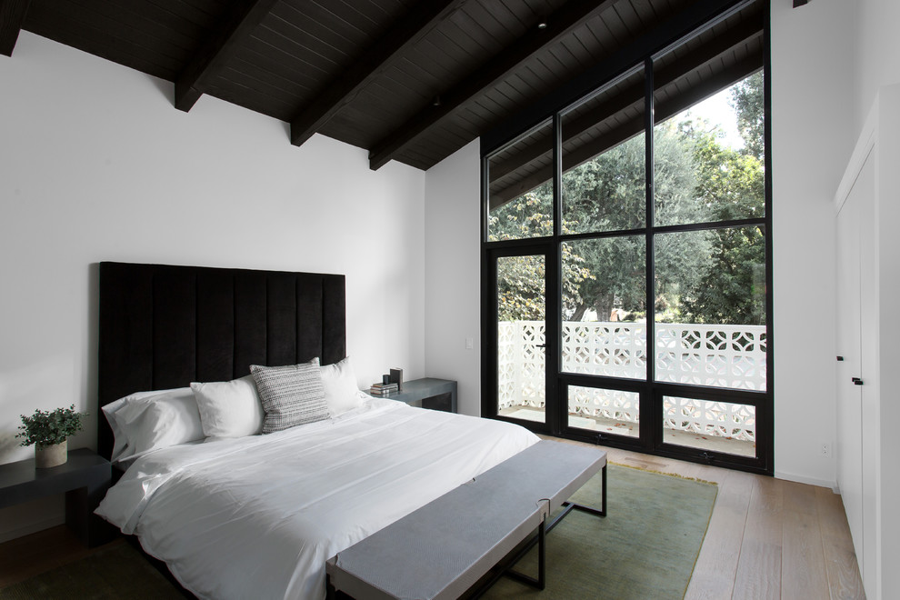 Modelo de dormitorio principal retro grande sin chimenea con paredes blancas, suelo de madera clara y suelo beige