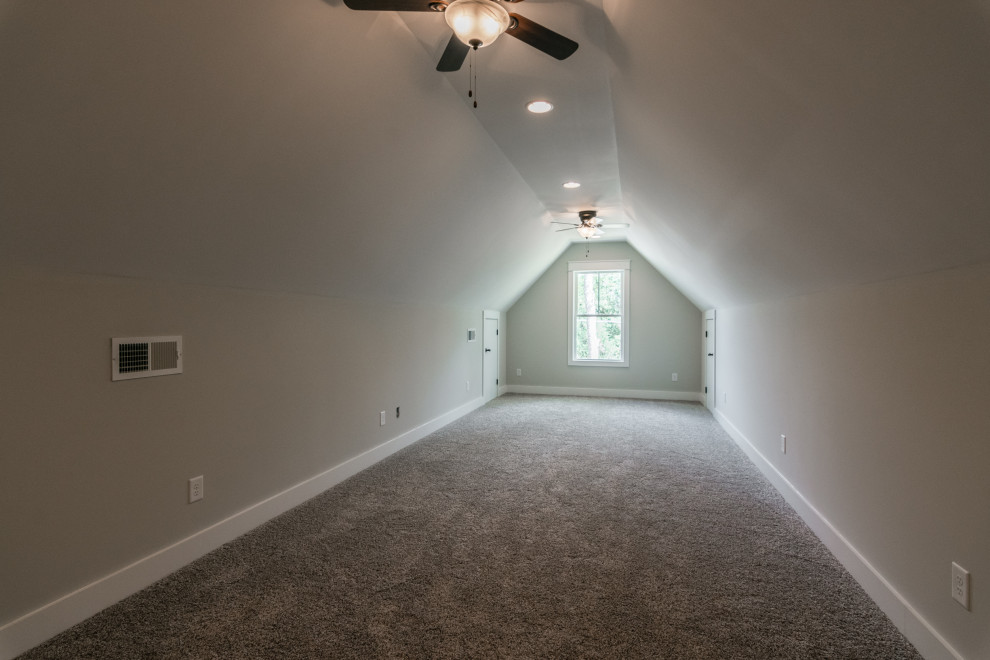 This is an example of a large country guest bedroom in Nashville with grey walls, carpet, no fireplace and grey floors.