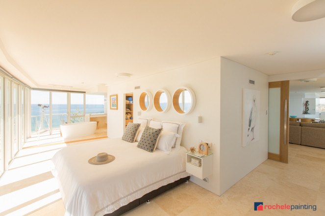 Diseño de dormitorio principal costero de tamaño medio con paredes blancas y suelo de travertino