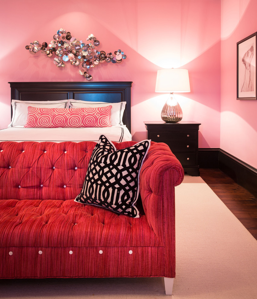 Cette image montre une grande chambre d'amis bohème avec un mur rose, un sol en bois brun et aucune cheminée.