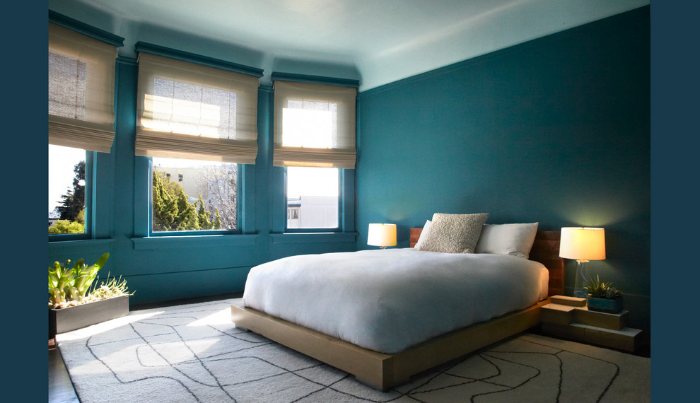 Réalisation d'une chambre parentale marine de taille moyenne avec un mur bleu et un sol en bois brun.