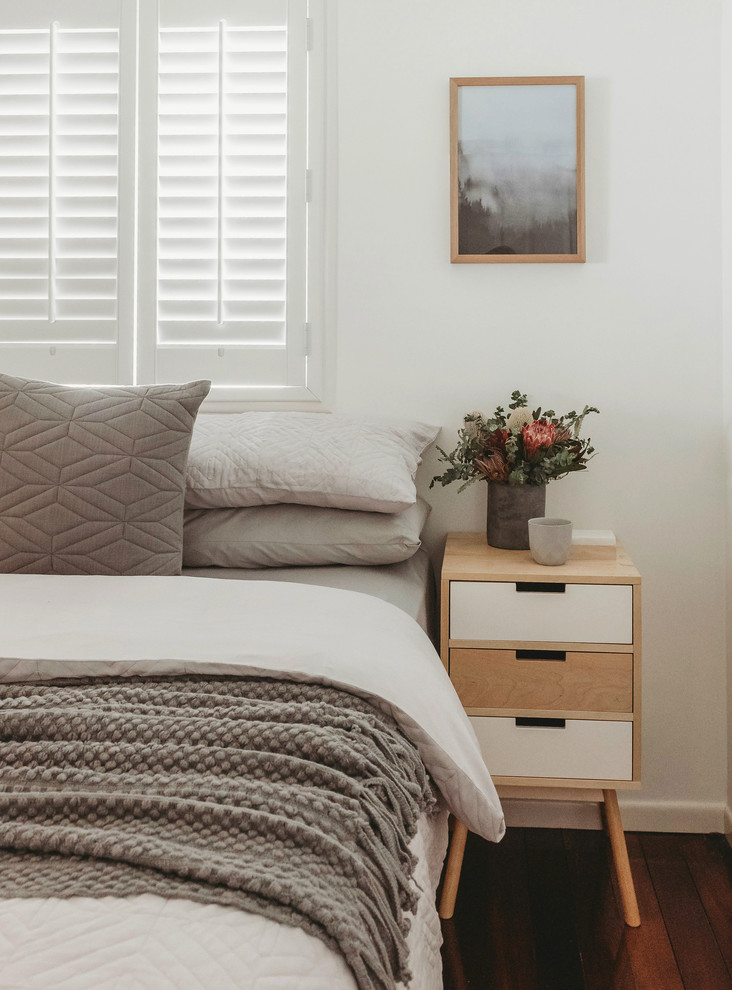 Foto de habitación de invitados nórdica de tamaño medio con paredes blancas, suelo de madera en tonos medios y suelo marrón