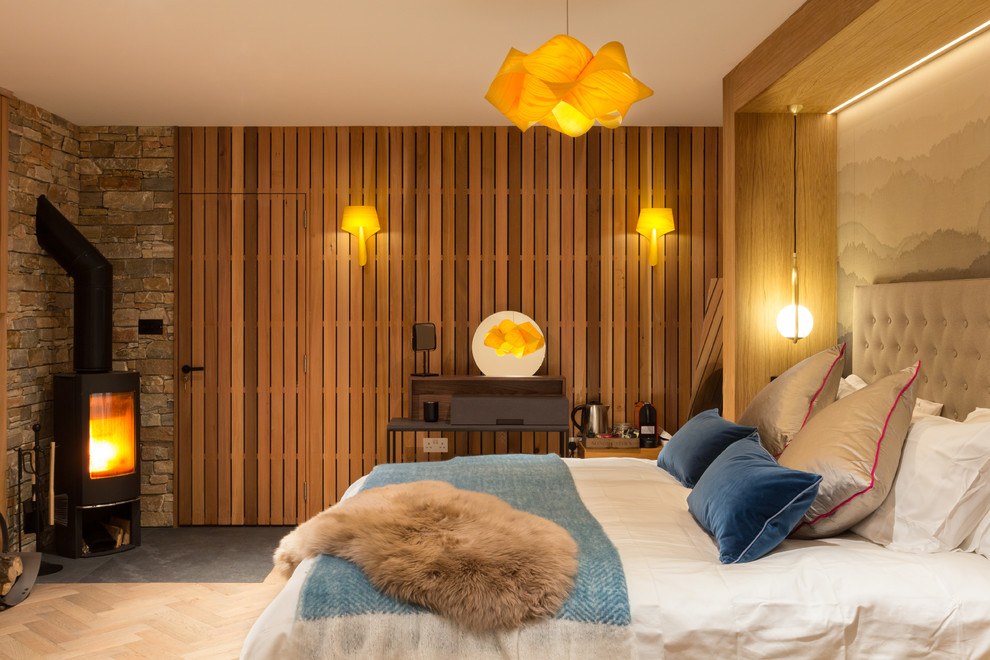 Foto de dormitorio principal actual de tamaño medio con suelo de madera clara y estufa de leña