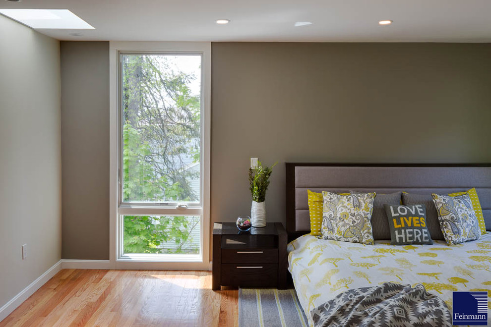 Diseño de dormitorio principal actual grande sin chimenea con paredes verdes y suelo de madera en tonos medios