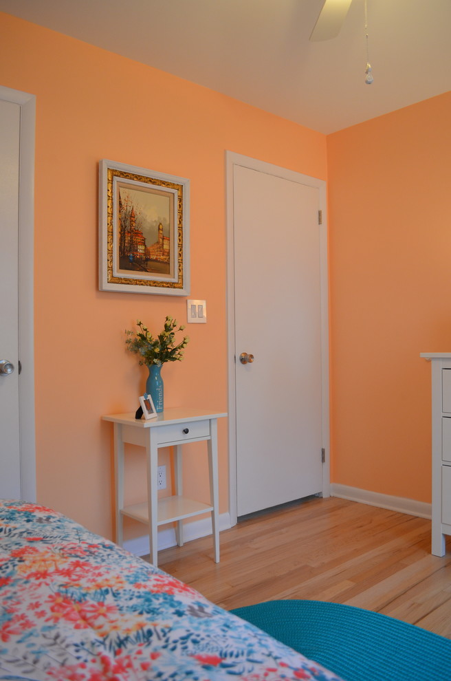 Immagine di una camera degli ospiti classica di medie dimensioni con pareti arancioni, parquet chiaro e nessun camino