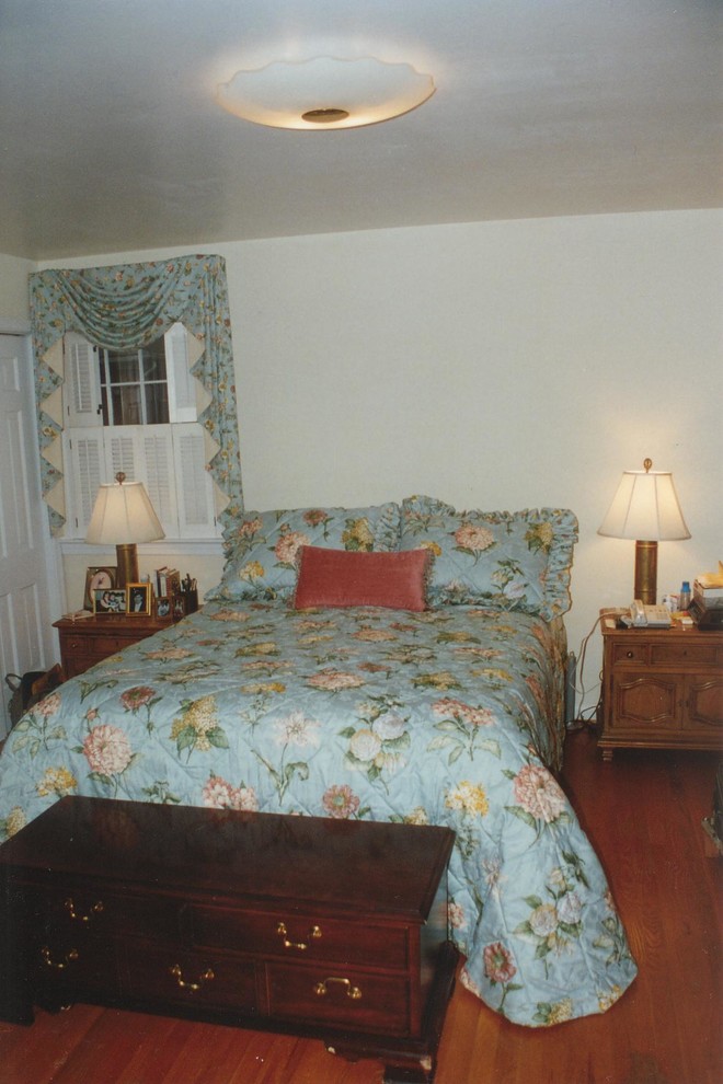 Modelo de dormitorio principal clásico de tamaño medio sin chimenea con paredes blancas, suelo de madera en tonos medios y suelo marrón