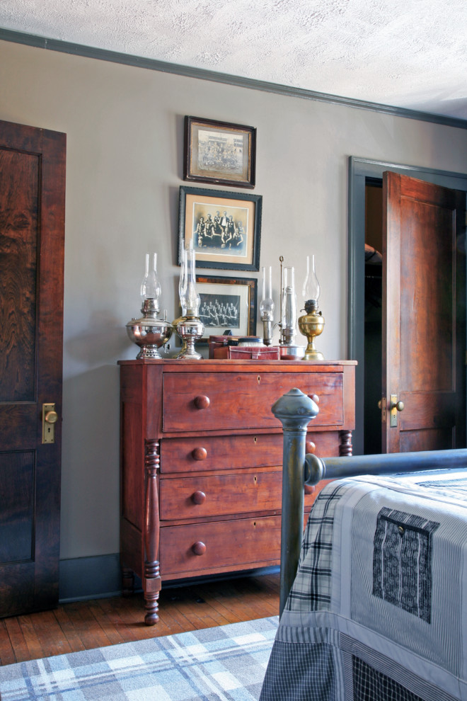 Idée de décoration pour une chambre d'amis champêtre de taille moyenne avec un mur gris et un sol en bois brun.