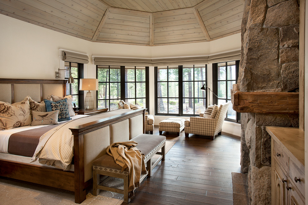 Rustic bedroom in Sacramento with white walls, dark hardwood flooring and a stone fireplace surround.