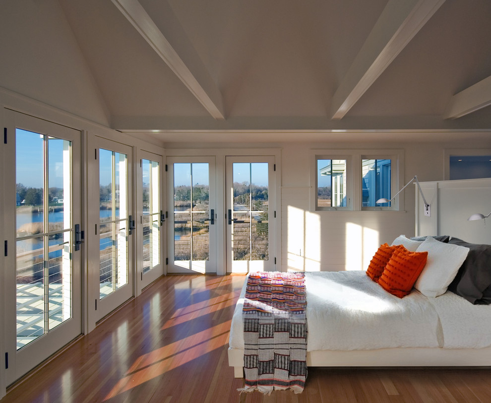 This is an example of a large beach style master bedroom in Boston with beige walls and medium hardwood flooring.
