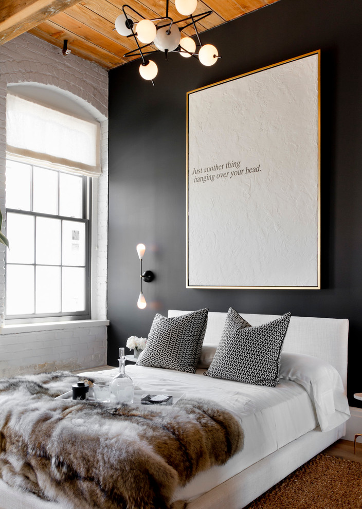 Inspiration pour une chambre design avec un mur noir et un sol en bois brun.