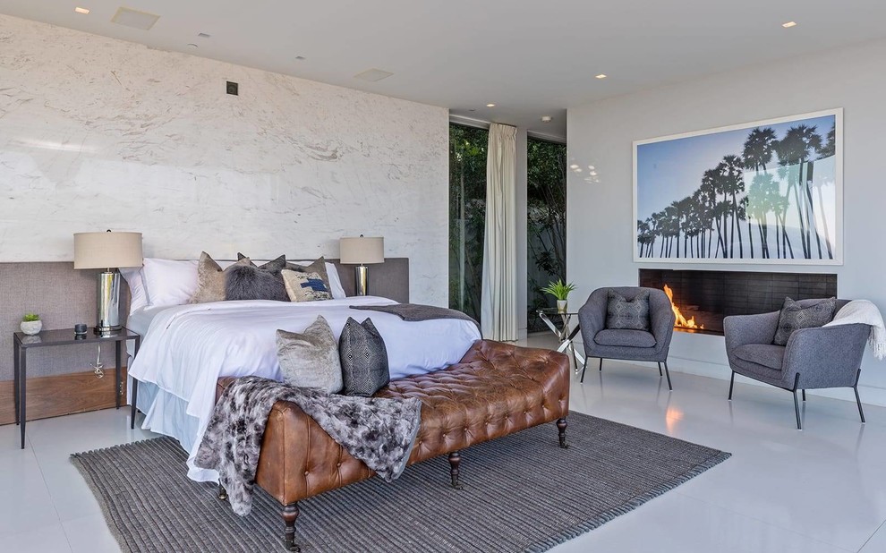 На фото: хозяйская спальня в современном стиле с белыми стенами, горизонтальным камином и серым полом с