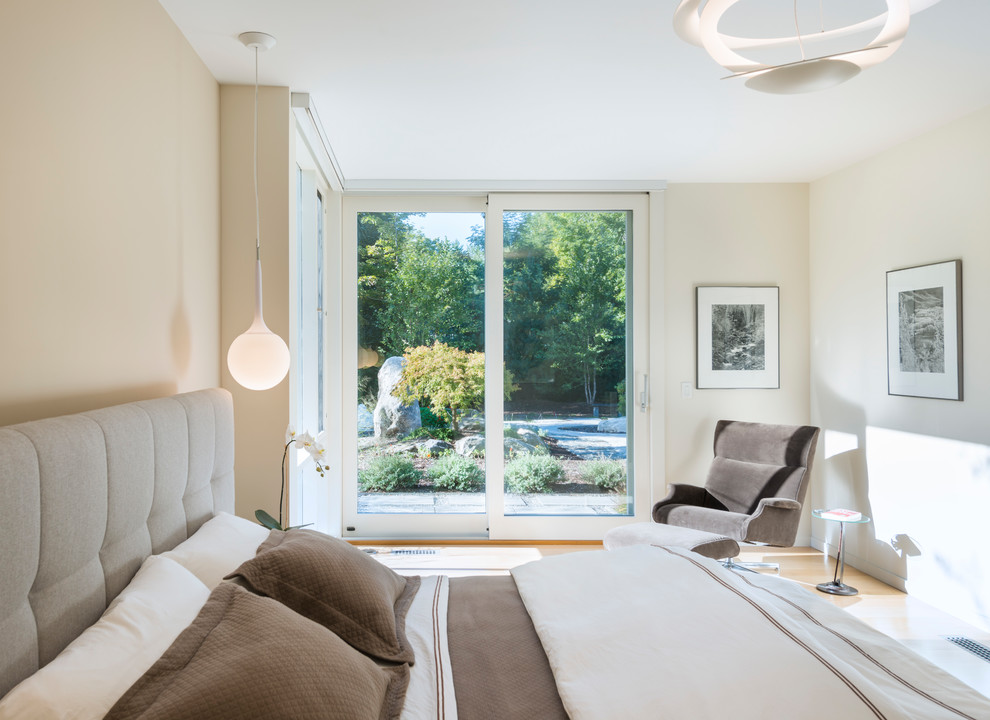 Modelo de habitación de invitados actual grande con paredes beige, suelo de madera clara y suelo beige