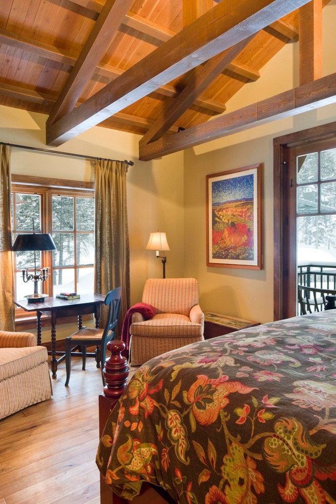 Example of a mid-sized mountain style master medium tone wood floor, brown floor, exposed beam and wood wall bedroom design in Albuquerque with beige walls and no fireplace
