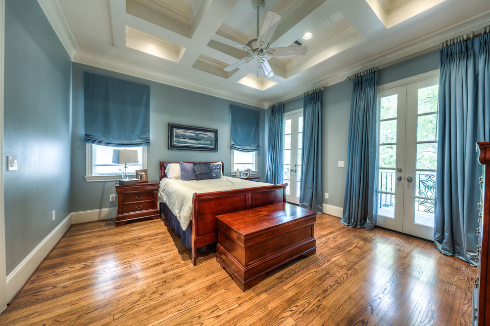 Ejemplo de dormitorio principal tradicional grande sin chimenea con paredes azules y suelo de madera en tonos medios