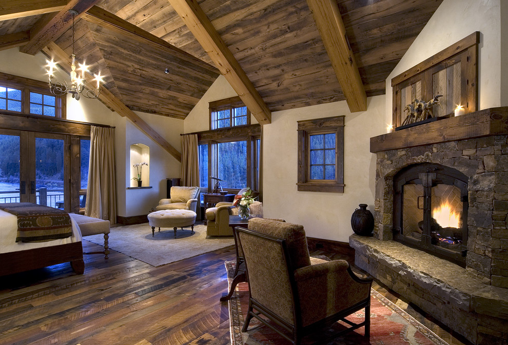Inspiration for a rustic master medium tone wood floor bedroom remodel in Denver with a standard fireplace and a stone fireplace