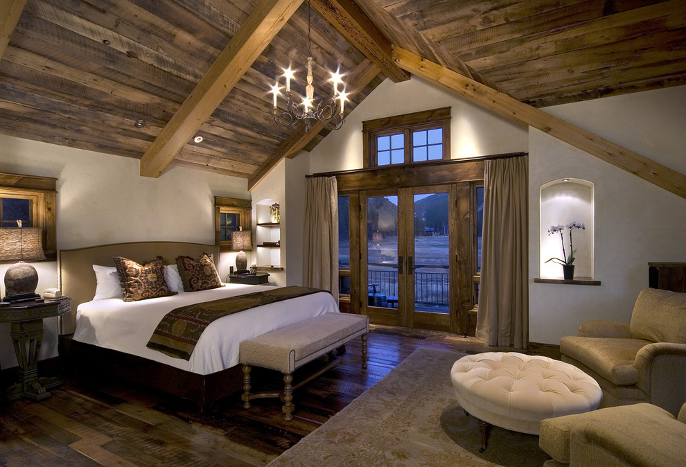 Foto de dormitorio principal rural con suelo de madera en tonos medios, todas las chimeneas y marco de chimenea de piedra