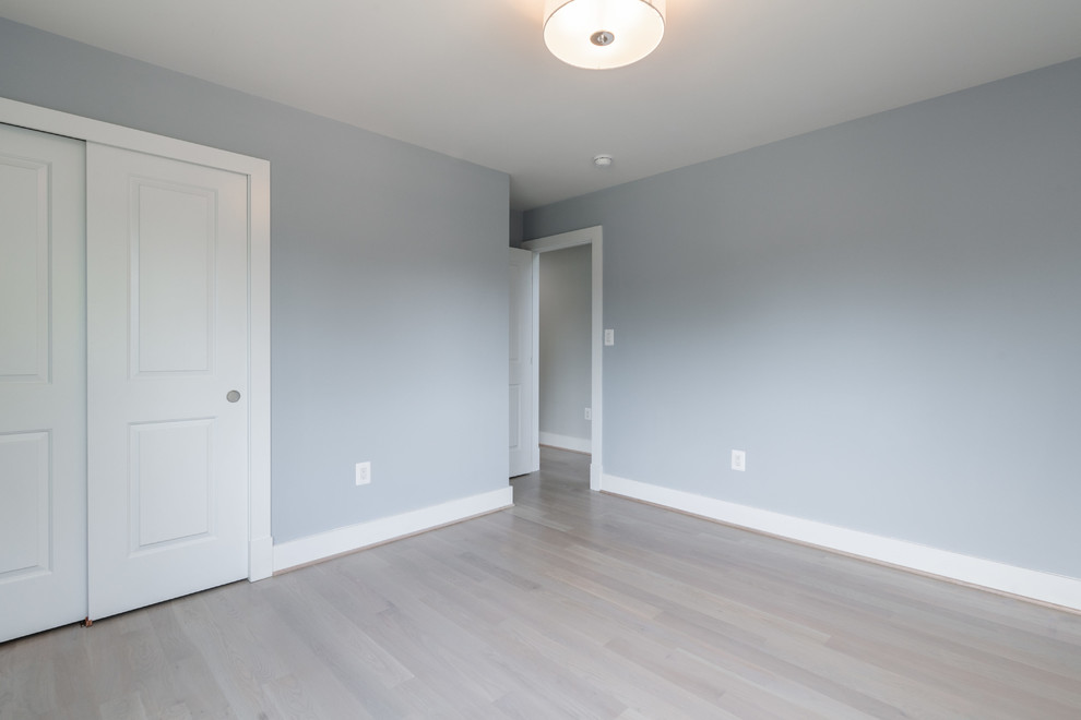 Modelo de dormitorio contemporáneo de tamaño medio con paredes grises, suelo de madera clara y suelo gris